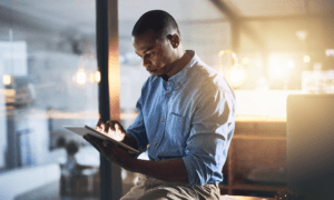 Person looking at mobile device while leaning on desk.